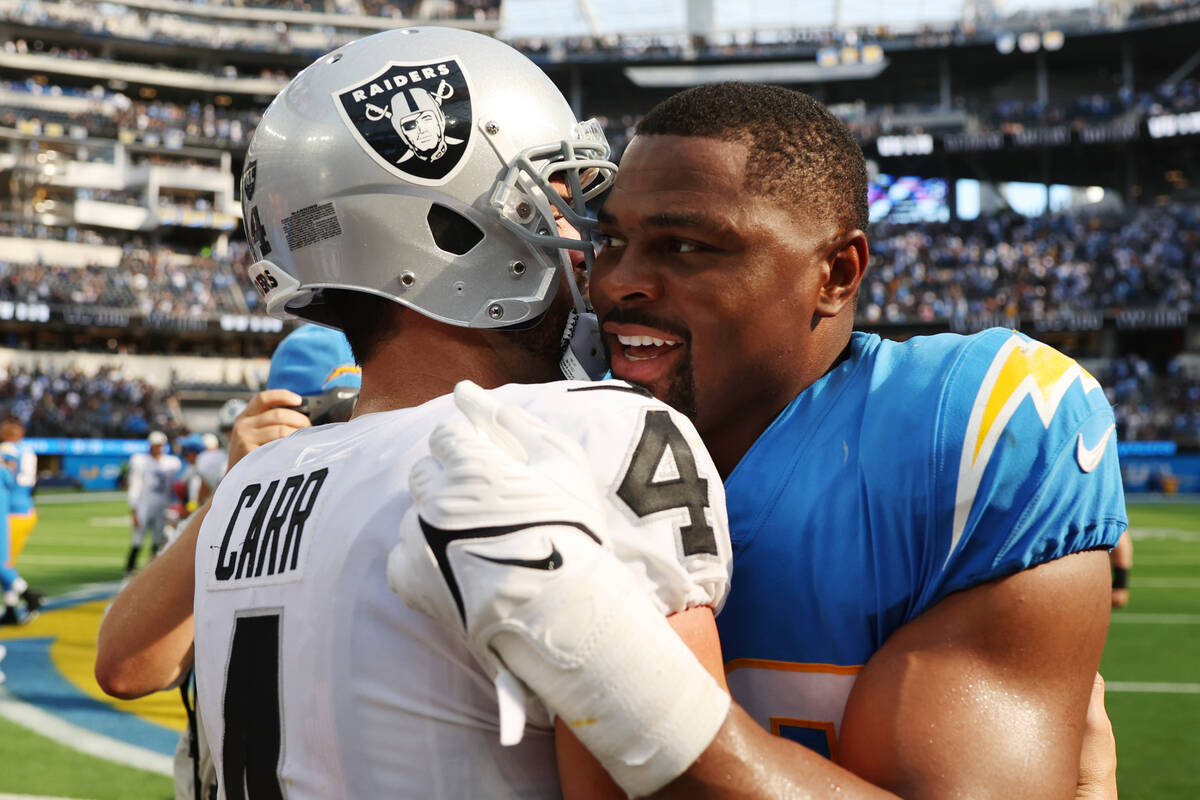 Raiders quarterback Derek Carr (4) embraces Los Angeles Chargers linebacker Khalil Mack (52) af ...