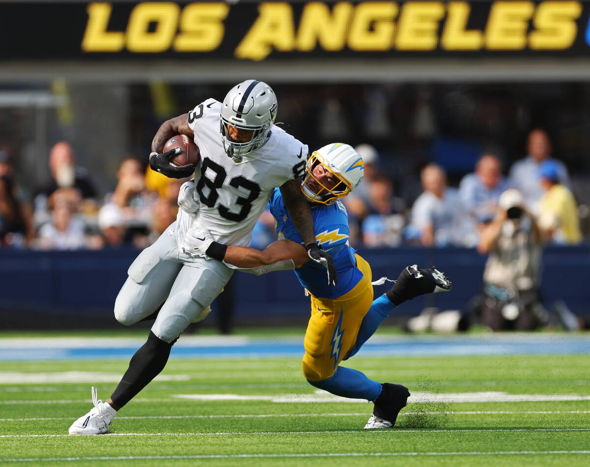 Raiders tight end Darren Waller (83) runs the ball under pressure from Los Angeles Chargers lin ...