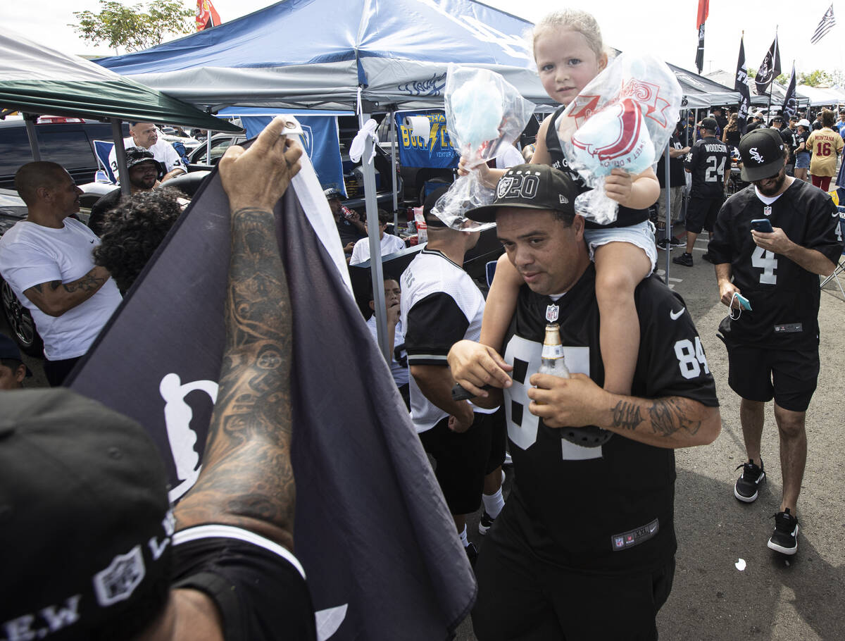 Raiders fans walk around a tailgate area before the start of an NFL game at SoFi Stadium on Sun ...