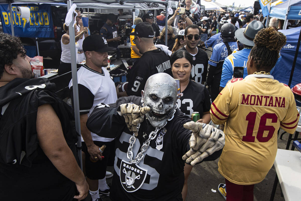 Raiders fans walk around a tailgate area before the start of an NFL game at SoFi Stadium on Sun ...