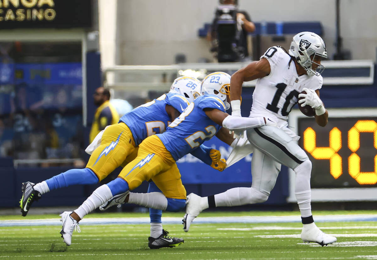 Raiders wide receiver Mack Hollins (10) runs the ball under pressure from Los Angeles Chargers ...