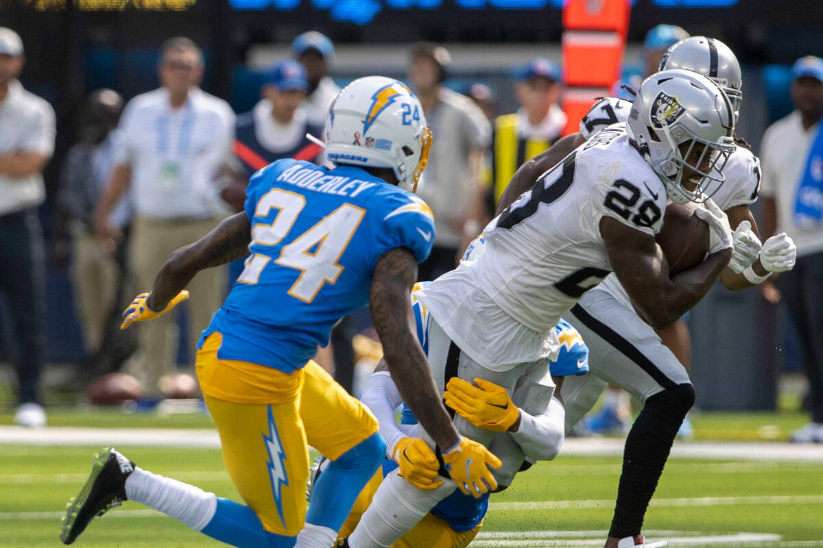 Raiders running back Josh Jacobs (28) runs with the football as Los Angeles Chargers safety Nas ...