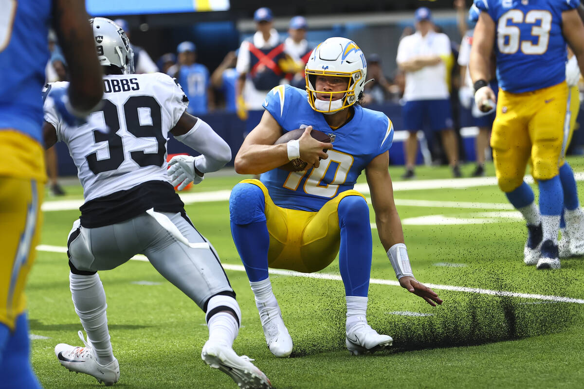 Los Angeles Chargers quarterback Justin Herbert (10) slides to the ground in front of Raiders c ...