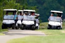 Former President Donald Trump, center cart, rides around his golf course at Trump National Golf ...