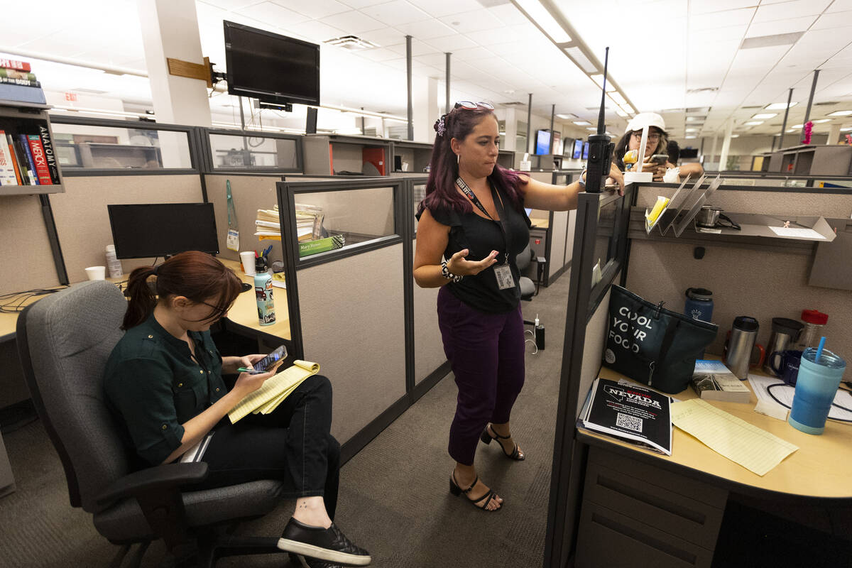 Reporters listen to a police scanner from the Las Vegas Review-Journal as police officers move ...