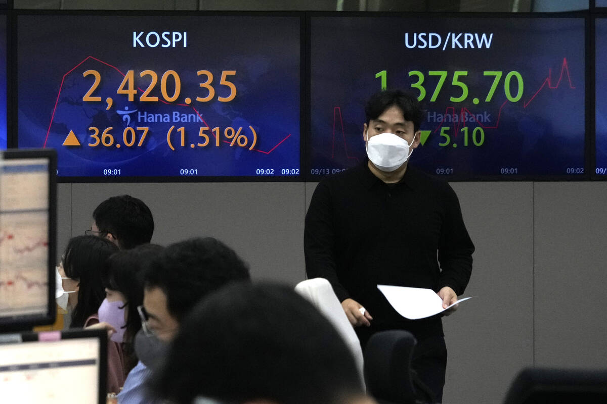 Currency traders watch computer monitors near the screens showing the Korea Composite Stock Pri ...