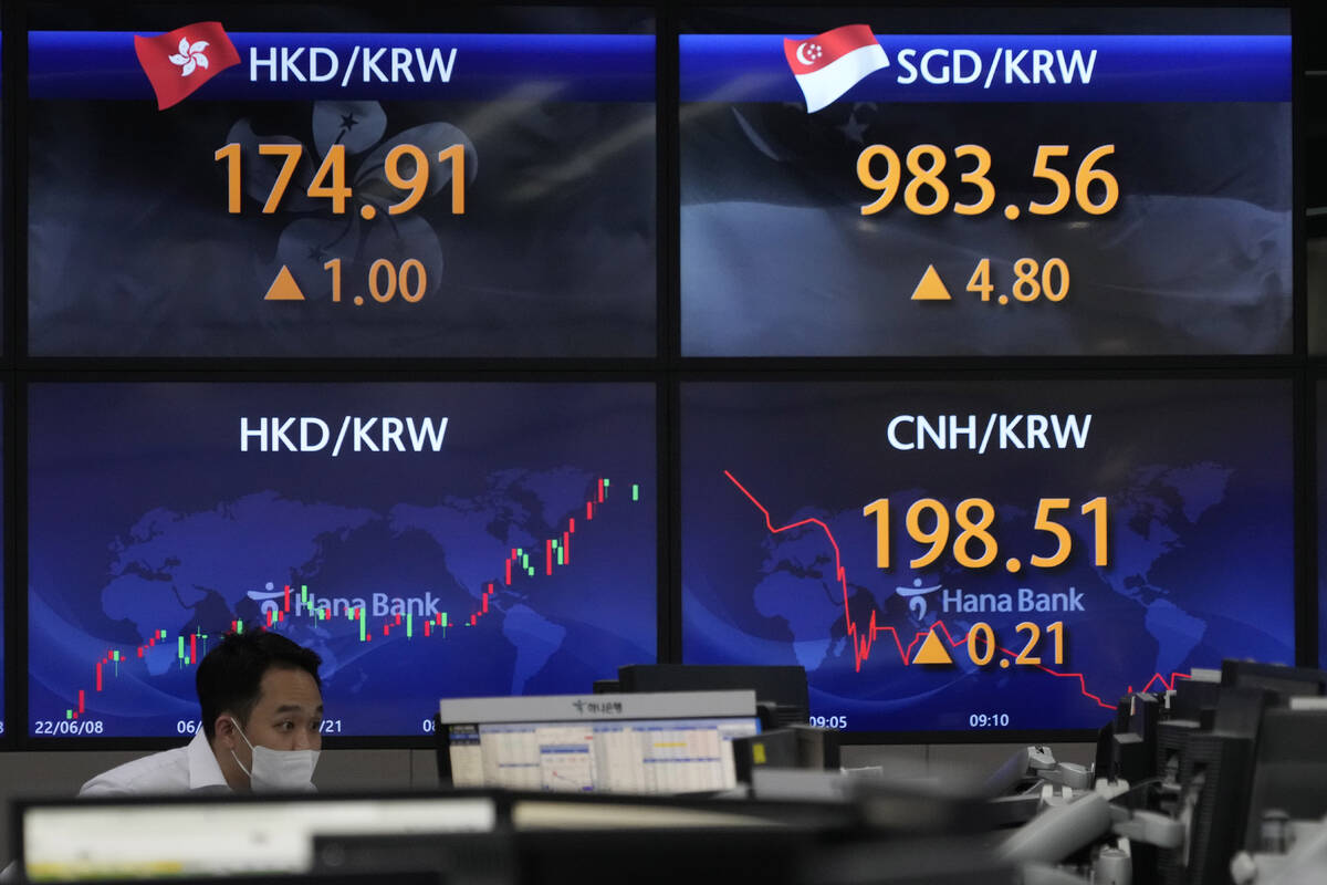 A currency trader watches computer monitors near the screens showing the foreign exchange rates ...