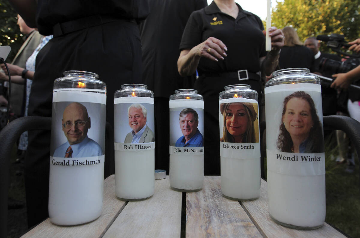 Photos of five journalists adorn candles during a vigil across the street from where they were ...