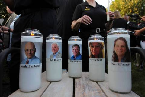 Photos of five journalists adorn candles during a vigil across the street from where they were ...
