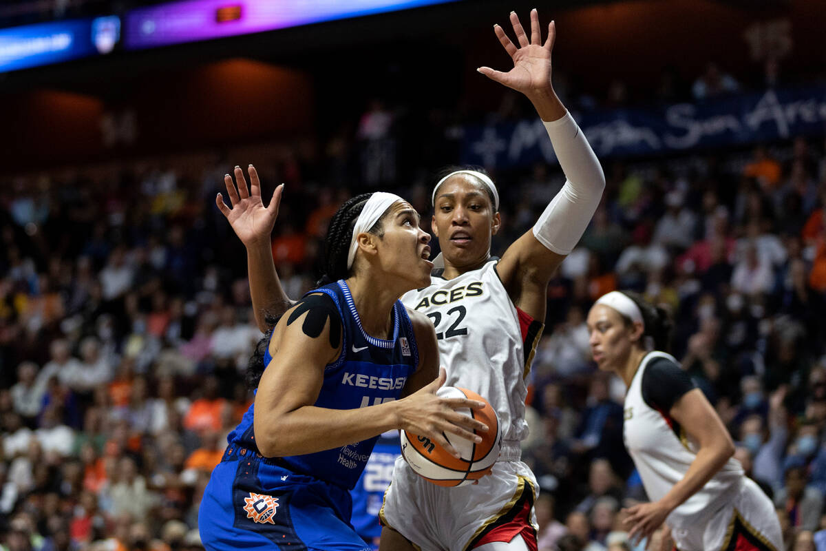 Connecticut Sun center Brionna Jones (42) drives around Las Vegas Aces forward A'ja Wilson (22) ...
