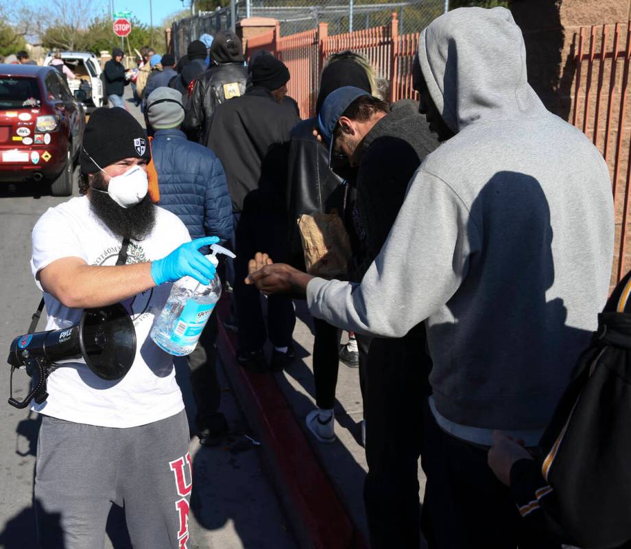 Joey Lankowski of homeless outreach organization Food Not Bombs squirts hand sanitizer for peop ...