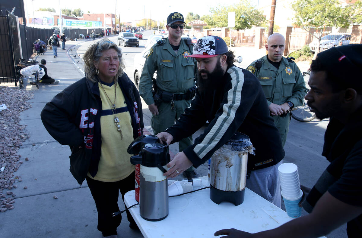 Las Vegas police watch as Joey Lankowski, center, cleans up the area where he was distributing ...