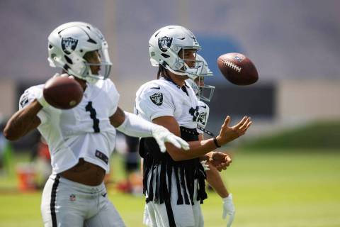 Raiders wide receiver Mack Hollins (10) juggles a football as wide receiver Tyron Johnson (1) t ...