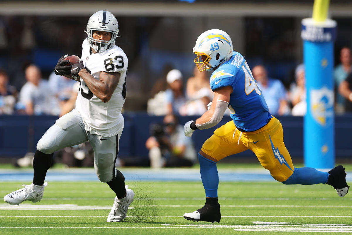 Raiders tight end Darren Waller (83) runs the ball under pressure from Los Angeles Chargers lin ...