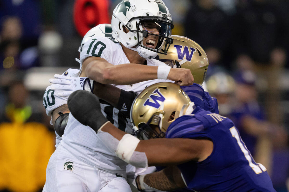 Michigan Statequarterback Payton Thorne is hit by Washington linebacker Alphonzo Tuputala, fron ...