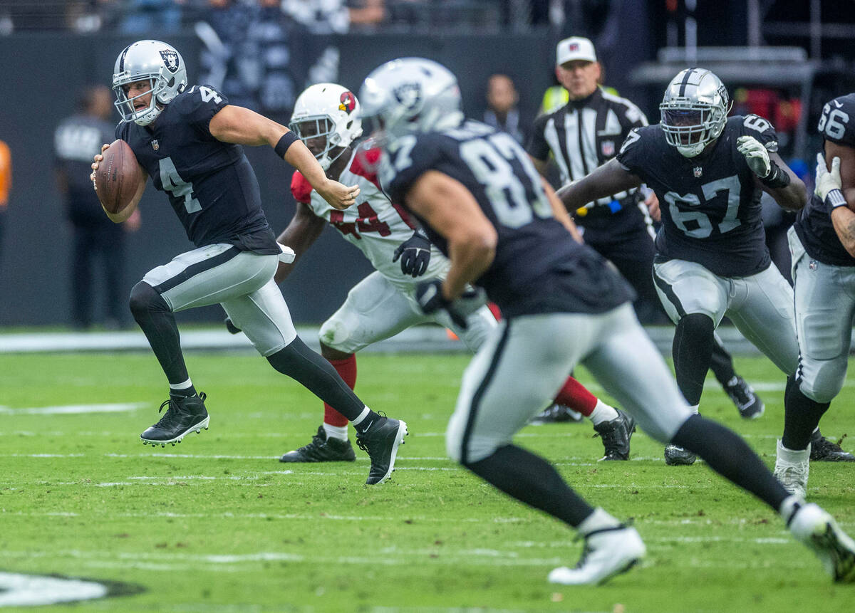Raiders quarterback Derek Carr (4) breaks free for a run pursued by Arizona Cardinals linebacke ...