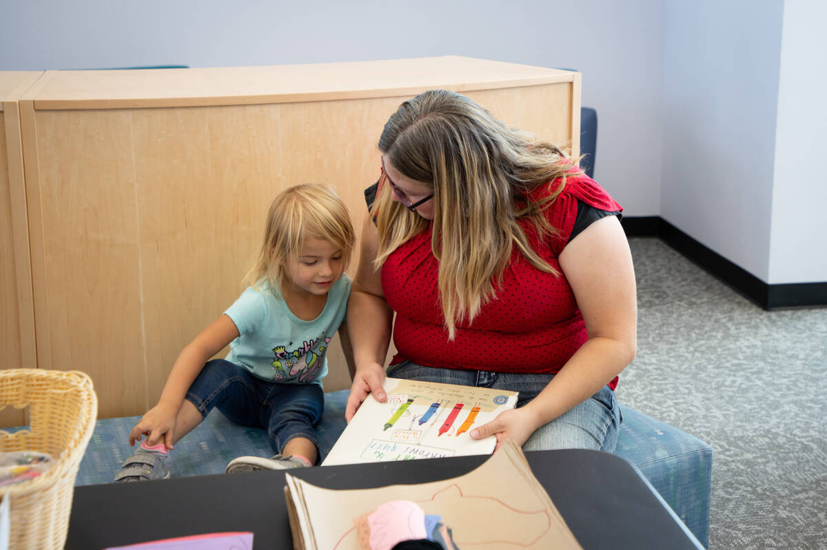 Tia Owens, right, shows a book to her daughter Melody, 2, in the new Henderson Library branch d ...