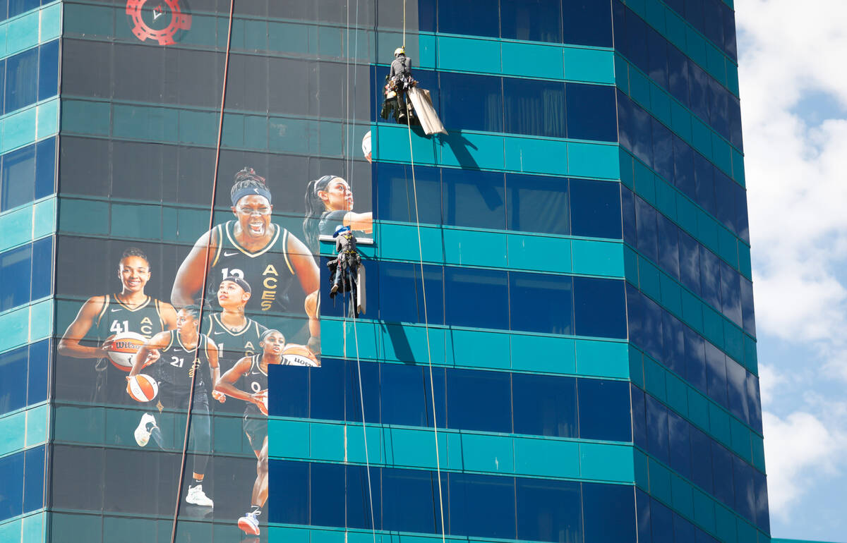 Screaming Images employees install a building wrap on MGM Grand to congratulate the Aces on Mon ...