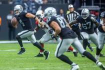 Raiders quarterback Derek Carr (4) breaks free for a run pursued by Arizona Cardinals linebacke ...