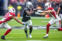 Raiders running back Josh Jacobs (28) splits the defense of Arizona Cardinals cornerback Marco ...