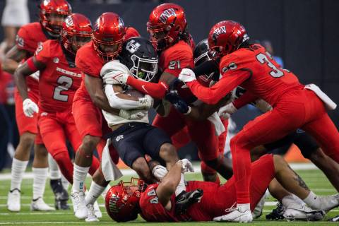 Utah State Aggies wide receiver Deven Thompkins is stacked up by UNLV Rebel defenders in the fi ...