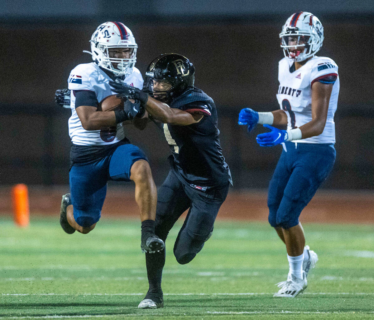 Liberty running back Isaiah Lauofo (3) leaps through a tackle attempt by Faith Lutheran's lineb ...
