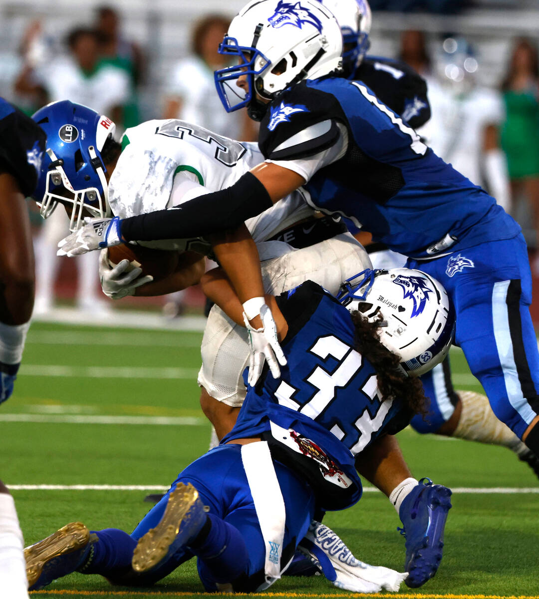 Green Valley High's running back Estaban Martinez (34) is sucked by Basic High's Miguel Barrang ...