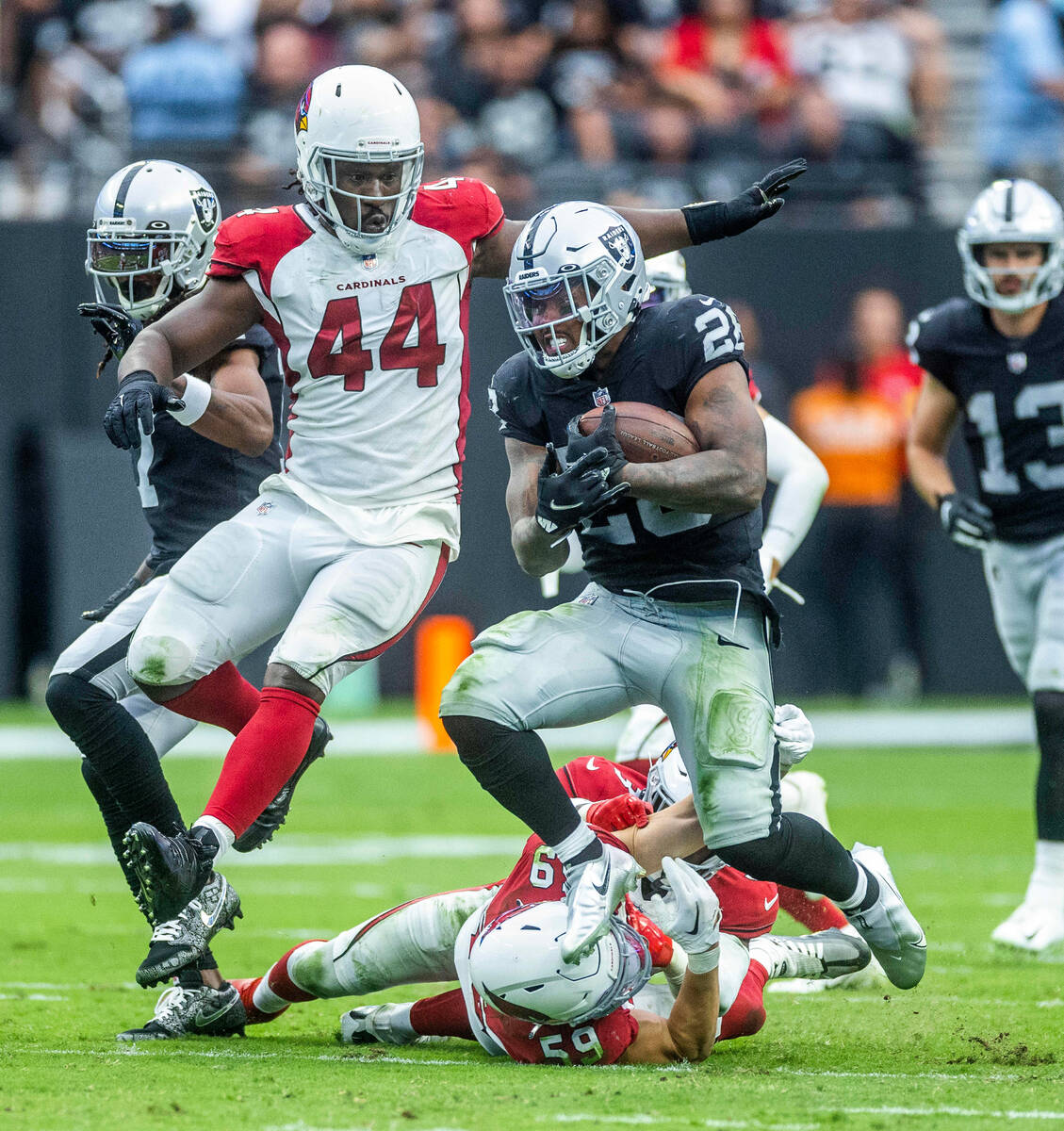 Raiders running back Josh Jacobs (28) leaps from a tackle attempt by Arizona Cardinals lineback ...