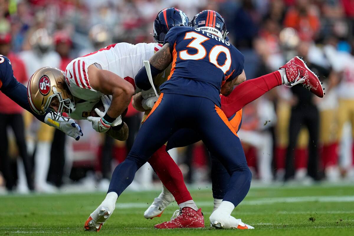 San Francisco 49ers tight end George Kittle, middle, is tackled by Denver Broncos safety Caden ...