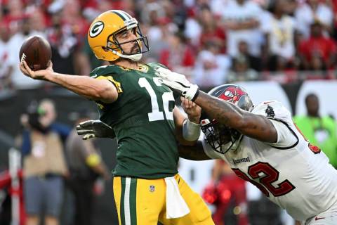 Green Bay Packers' Aaron Rodgers throws while being hit by Tampa Bay Buccaneers' William Gholst ...
