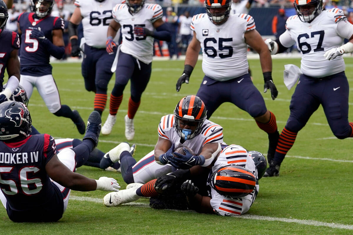 Chicago Bears running back Khalil Herbert, center, reaches over offensive tackle Braxton Jones, ...