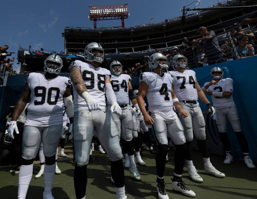 Raiders defensive end Maxx Crosby (98) and Raiders quarterback Derek Carr (4) get ready to lead ...