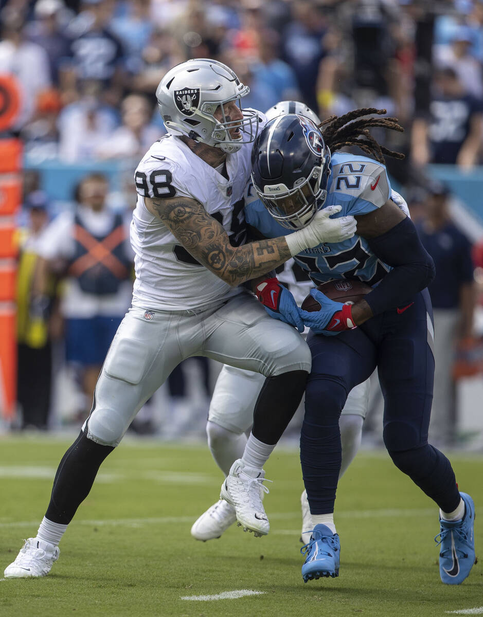 Raiders defensive end Maxx Crosby (98) stops Tennessee Titans running back Derrick Henry (22) d ...
