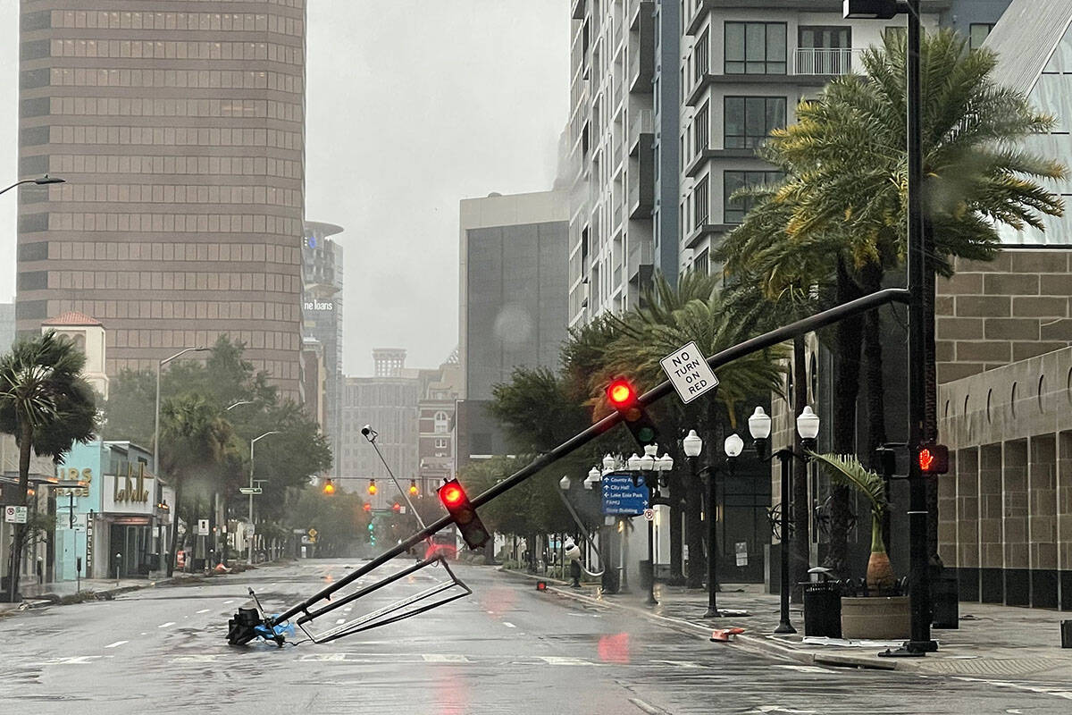 A stoplight pole blown down by Hurricane Ian winds, rests on Orange Avenue in Downtown Orlando, ...
