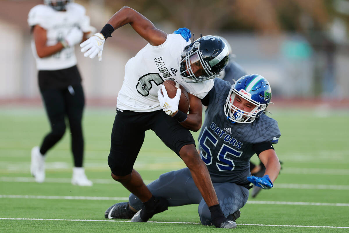 Desert Pines' Massiah Mingo (6) deflects a tackles by Green Valley's Jayden Green (55) in the f ...