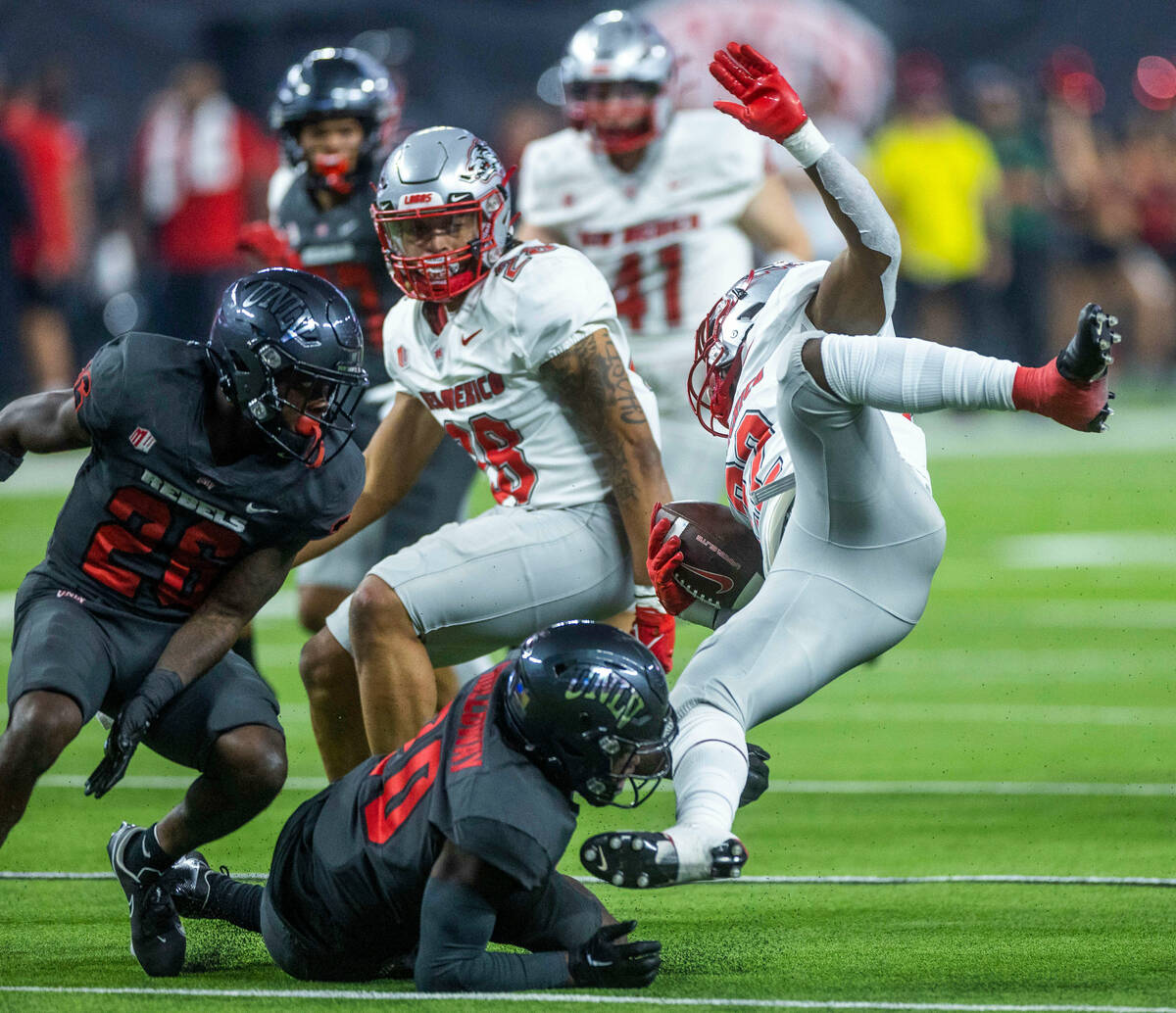 UNLV Rebels defensive back Trenton Holloway (20) upends New Mexico Lobos running back Christian ...