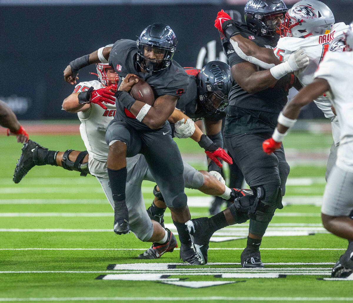 UNLV Rebels running back Aidan Robbins (9) blasts up the middle past New Mexico Lobos defensive ...