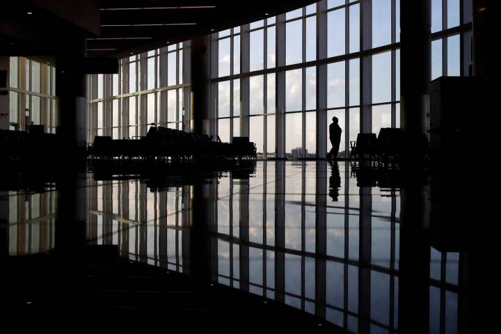 FILE - In this June 1, 2020 file photo, a woman looks through a window at a near-empty terminal ...