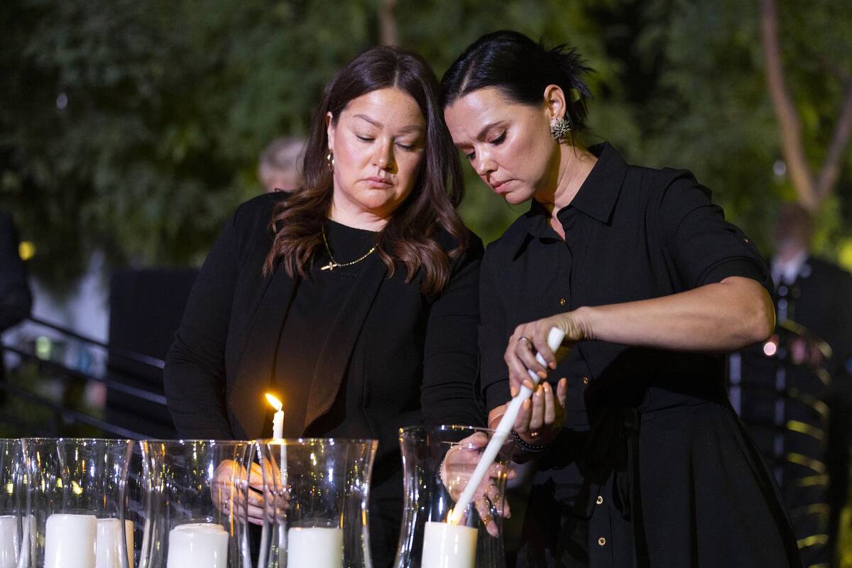 City of Las Vegas employees Maria Bigas, left, and Jasmine Freeman, left, light up a candle for ...