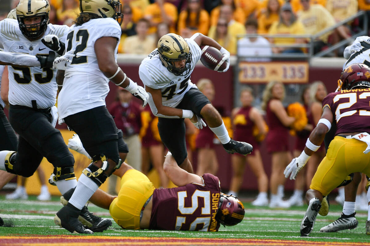 Purdue running back Devin Mockobee (45) runs over Minnesota linebacker Mariano Sori-Marin (55) ...