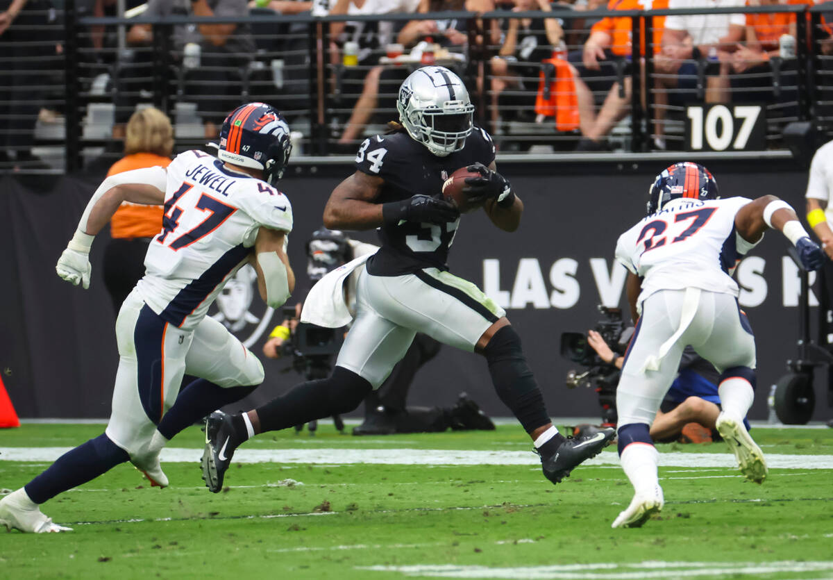 Raiders running back Brandon Bolden (34) runs the ball between Denver Broncos linebacker Josey ...