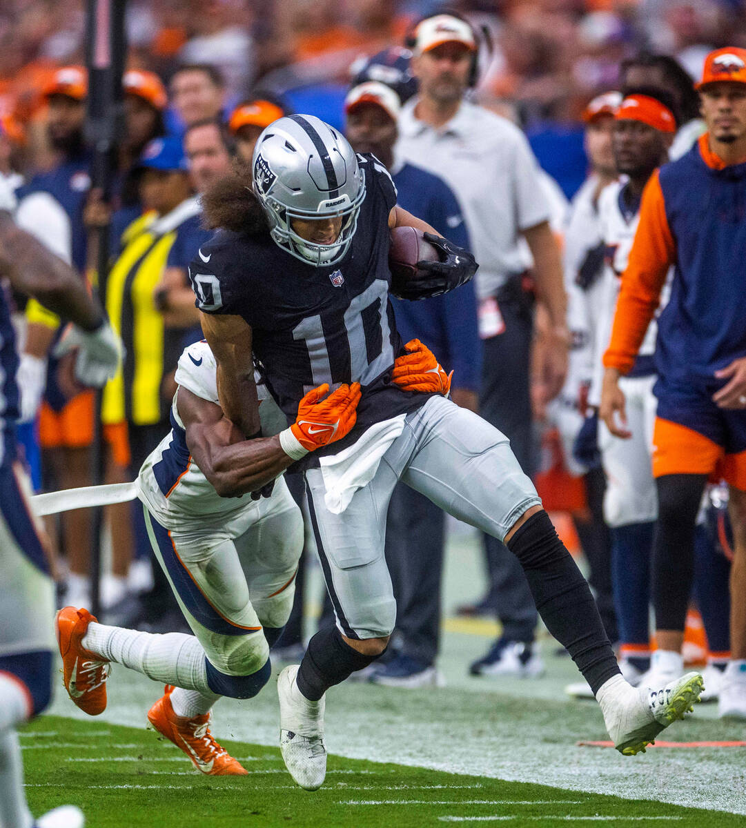 Raiders wide receiver Mack Hollins (10) fights off a Denver Broncos tackle during the second ha ...