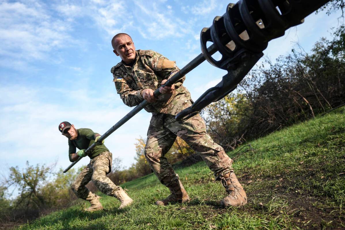 Ukrainian soldiers clean the muzzle of Ukrainian howitzer D-30 near Siversk, Donetsk region, Uk ...