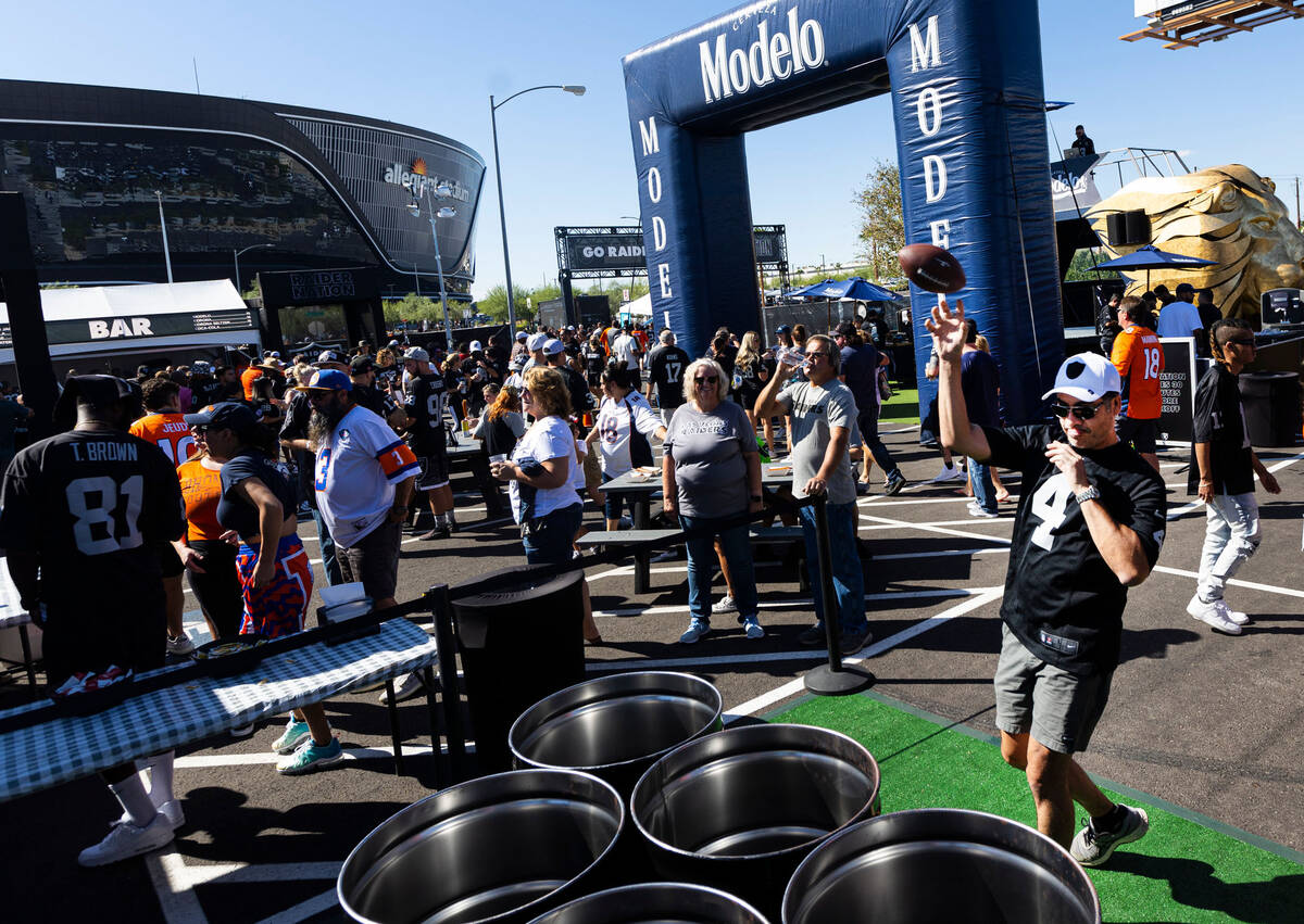 Raiders fan Jorge Banos, of Edmonton, Canada, throws a pass at the Modelo tailgate zone before ...