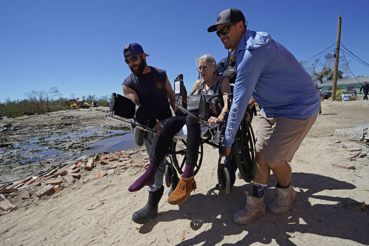 Rescuers help evacuate Suzanne Tomlinson, a resident who rode out the storm, as they carry her ...