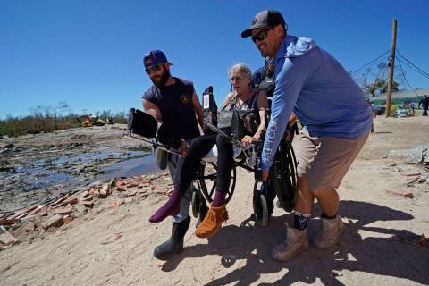 Rescuers help evacuate Suzanne Tomlinson, a resident who rode out the storm, as they carry her ...