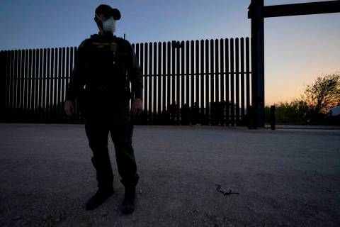 In this March 21, 2021 photo, a U.S. Customs and Border Protection agent looks on near a gate o ...