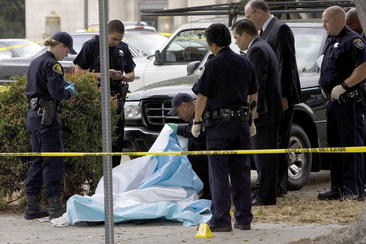 Oakland (Calif.) police officers investigate the scene where Oakland Post editor Chauncey Baile ...