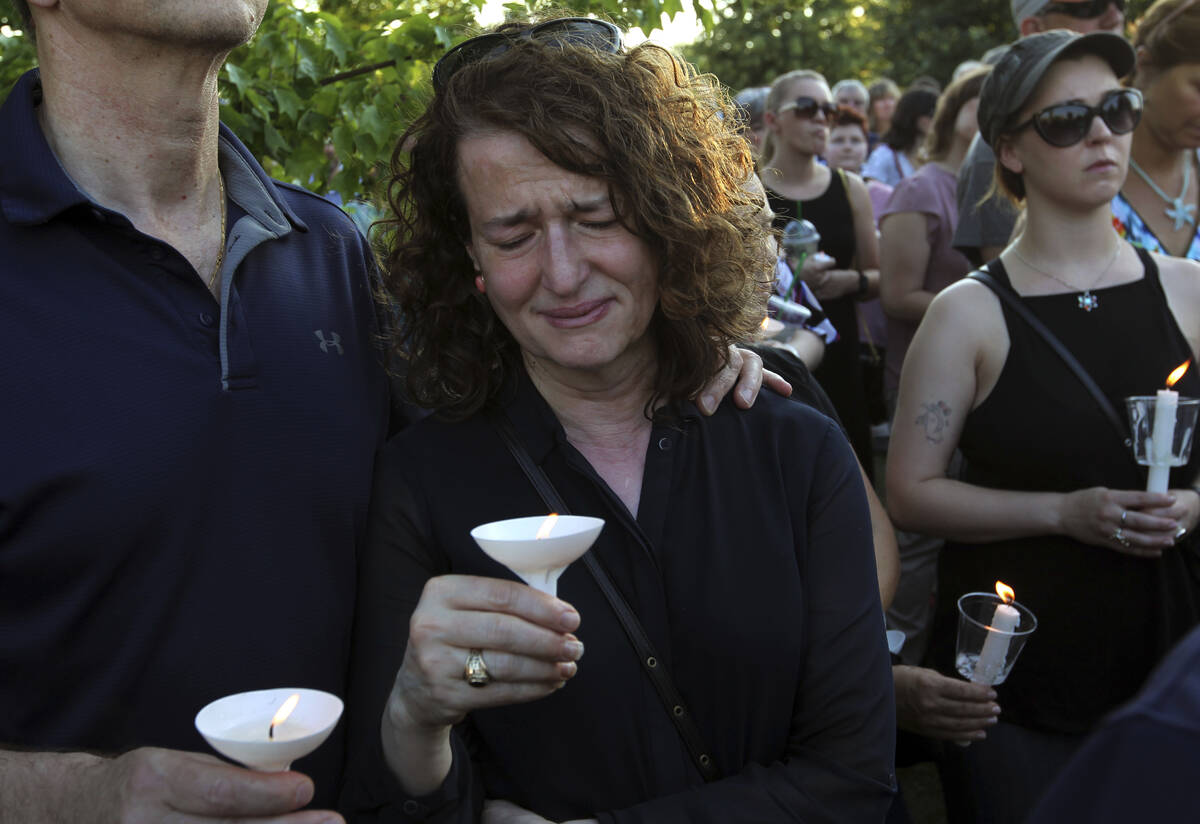 People gather for a candlelight vigil across the street from where five journalists were slain ...
