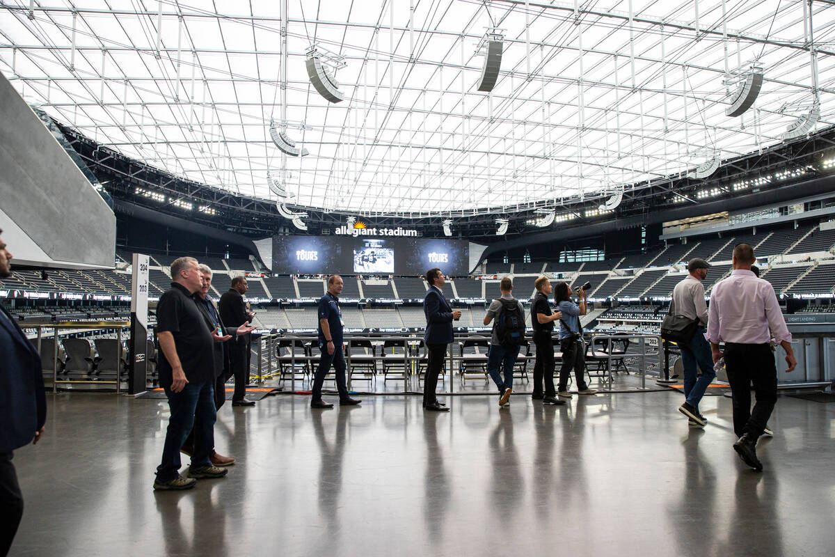 Employees of MatSing walk the concourse during a tour of Allegiant Stadium with lens antenna te ...